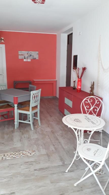 - un salon avec une table, des chaises et un mur rouge dans l'établissement La rezztella, à Fondi