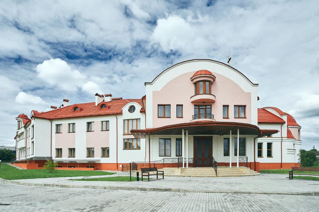 un gran edificio blanco con techo rojo en Hotel Patriarshyi en Leópolis