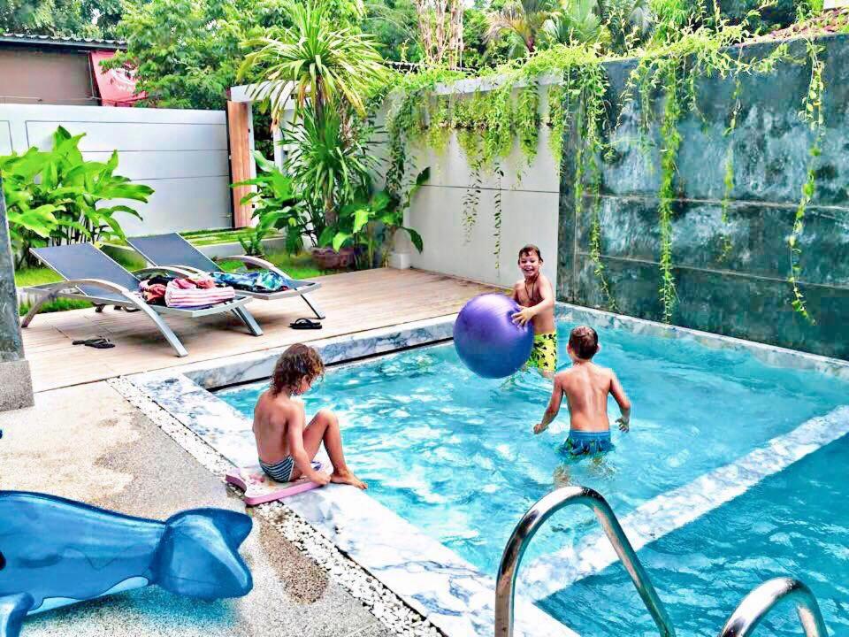 a family playing in a swimming pool in a backyard at Lemonade Phuket Hotel -SHA Plus in Chalong