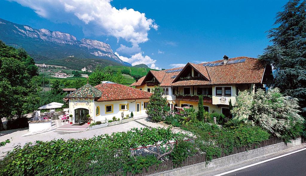 a large house with a mountain in the background at Hotel Unterrain in Appiano sulla Strada del Vino