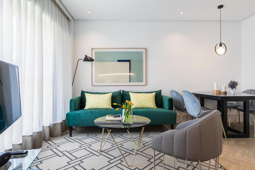 uma sala de estar com um sofá verde e uma mesa em Feelathome Waldorf Suites Apartments em Madrid