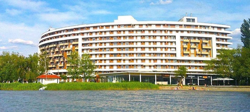 a large building sitting next to a body of water at ‘Good Feelings’ in Siófok