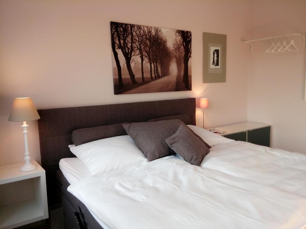 a bedroom with a white bed with a picture on the wall at Ferienwohnung Linsenstrasse 13 in Mühlhausen