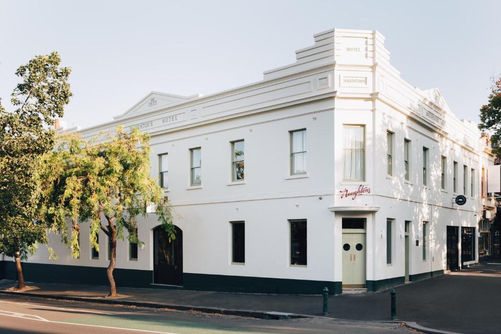 um edifício branco na esquina de uma rua em Naughtons Hotel em Melbourne