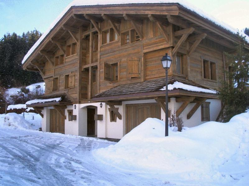 uma grande casa de madeira com neve em frente em Chalets de Julie em Megève