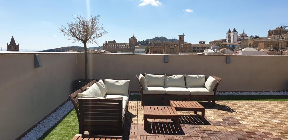 een patio met 2 stoelen en een bank op een dak bij Apartamentos AL-QAZERES LUXURY La Concepción in Cáceres