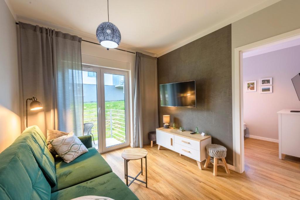 a living room with a green couch and a window at Apartament Tajemnica Izerska - 5D Apartamenty in Świeradów-Zdrój
