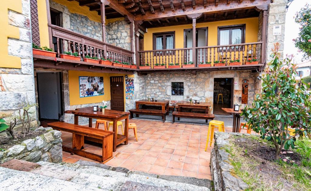 patio z drewnianymi stołami i ławkami przed budynkiem w obiekcie Albergue Santa Marina w mieście Buelna