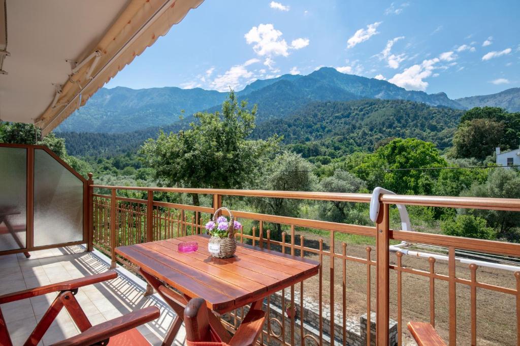 a wooden table on a balcony with a view of mountains at Dryades Apartments & Studios in Skala Potamias