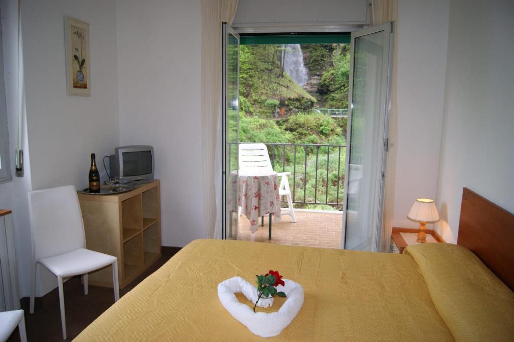 a bedroom with a bed and a balcony with a view at Albergo Ristorante Pace in Bognanco