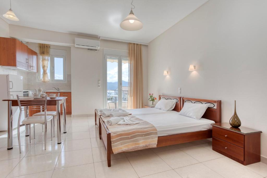 a bedroom with a bed and a kitchen with a table at Niovi Luxury Apartments in Loutra Edipsou