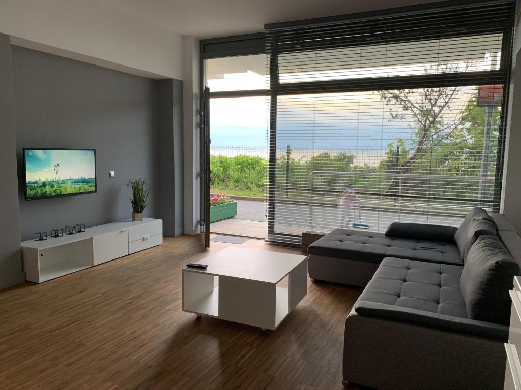 a living room with a couch and a large window at Apartament na Klifie DUNE in Ustronie Morskie