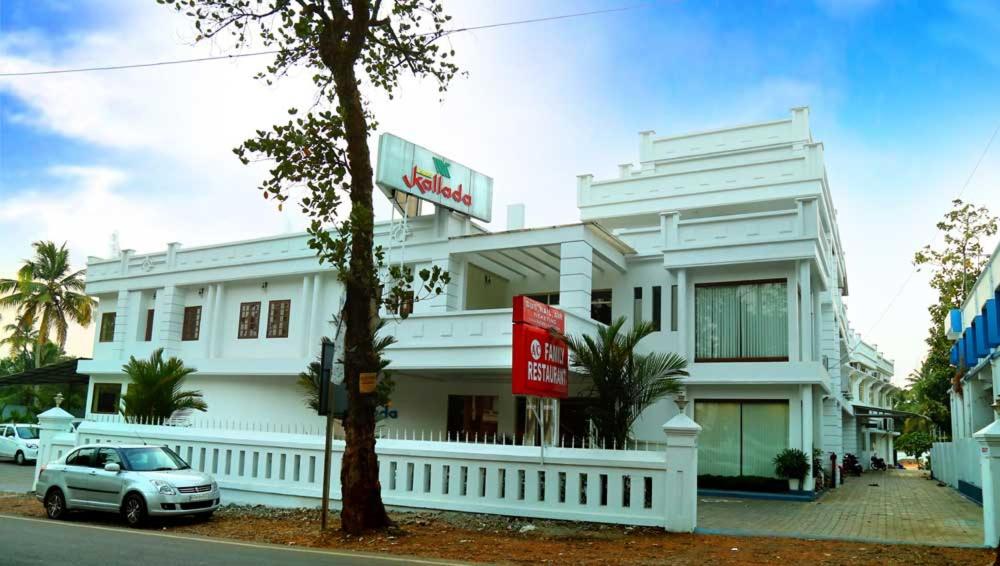 Un edificio blanco con un coche aparcado delante. en Kallada hotels, en Trichūr