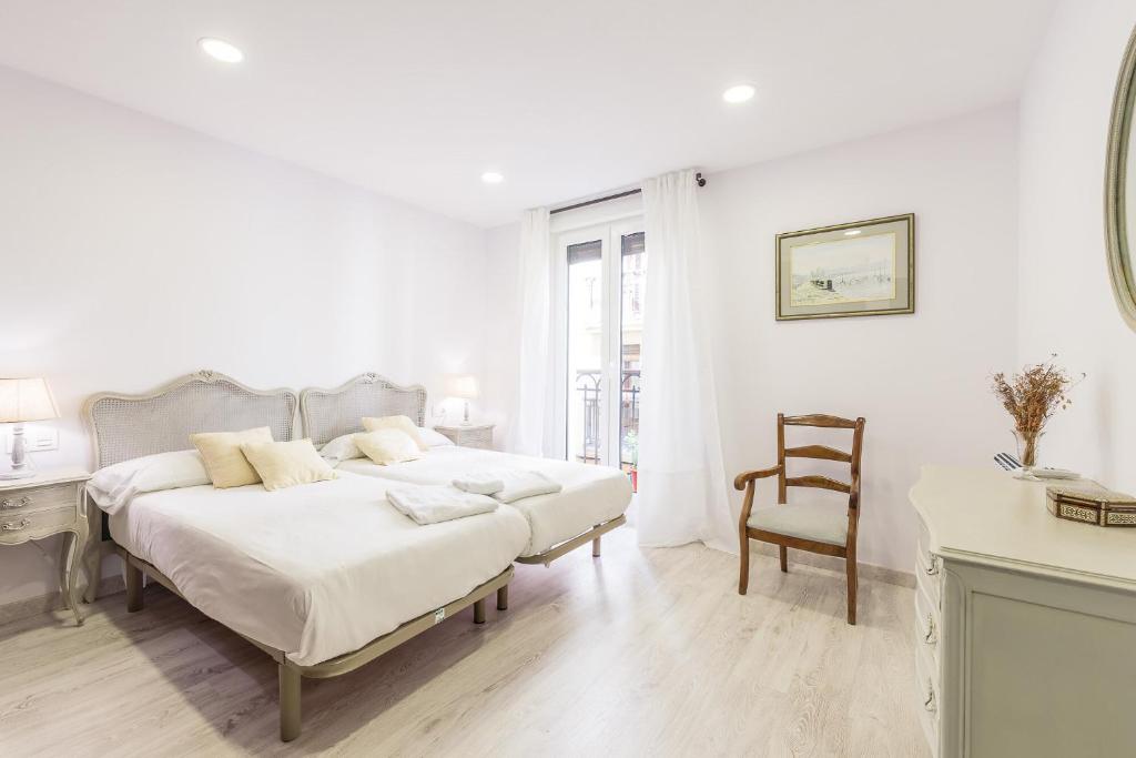 サン・セバスティアンにあるPuerto - Local Rentssの白いベッドルーム(ベッド1台、椅子付)