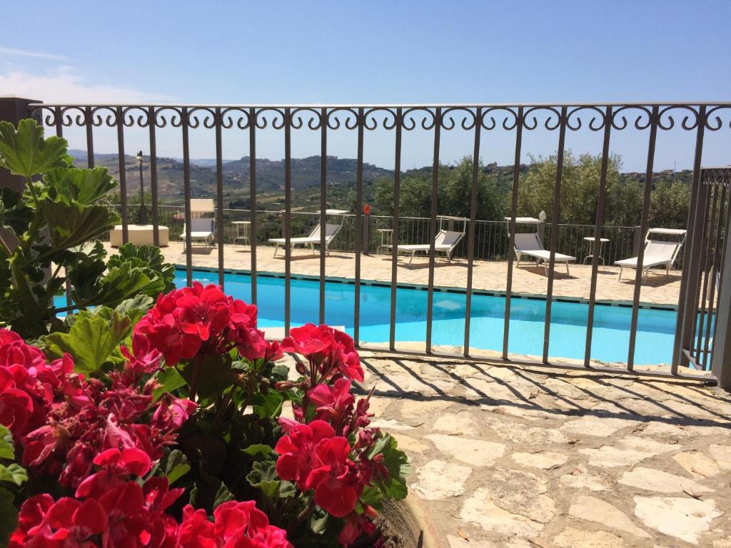 a view of a swimming pool with red flowers at agriturismo roba degli ulivi in Agrigento
