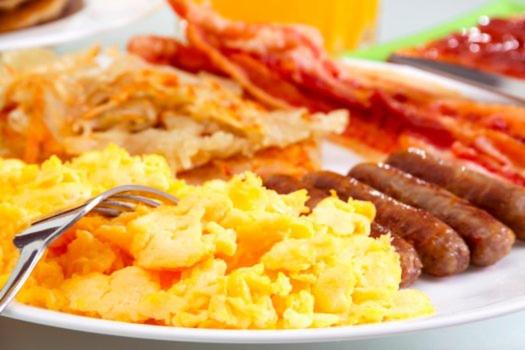 a plate of breakfast food with eggs sausage and bacon at Hotel Palms Central in Palmira