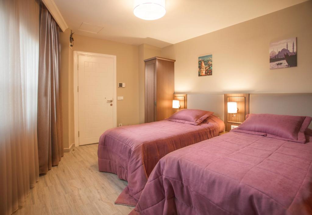 a bedroom with two beds with purple blankets at HALİT VARGÜN APART in Istanbul