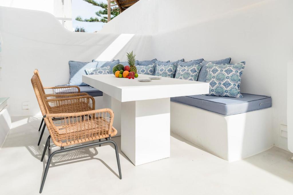 a white table and chairs with a bowl of fruit on it at Mykonian Mews Luxury Suites in Psarou