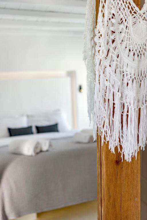 a white lace curtain on a wooden post in a bedroom at Mykonian Mews Luxury Suites in Psarou