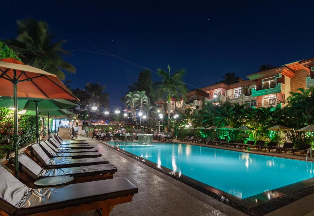 a pool at a resort with lounge chairs and an umbrella at Somy Plaza Calangute Goa - Formerly Somy Resort in Calangute