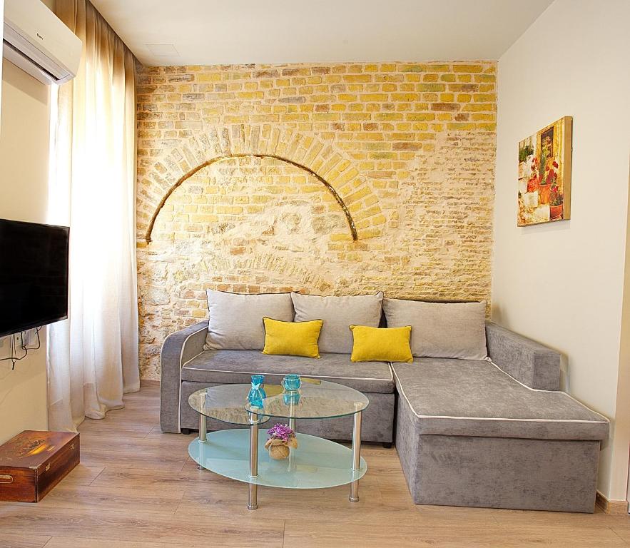 uma sala de estar com um sofá e uma parede de tijolos em Liston Inn Suites (Piazza) - Heart of Corfu Old Town em Corfu Town