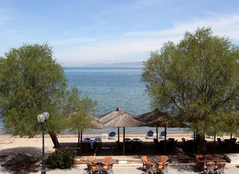 a beach with chairs and umbrellas and the ocean at Noni Rooms in Agia Triada