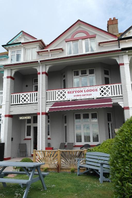 un edificio con una mesa de picnic delante de él en Sefton Lodge SEAFRONT ,PANORAMIC SEA VIEW ENSUITE BALCONY ROOMS AVAILABLE, GUEST GARDEN, en Paignton