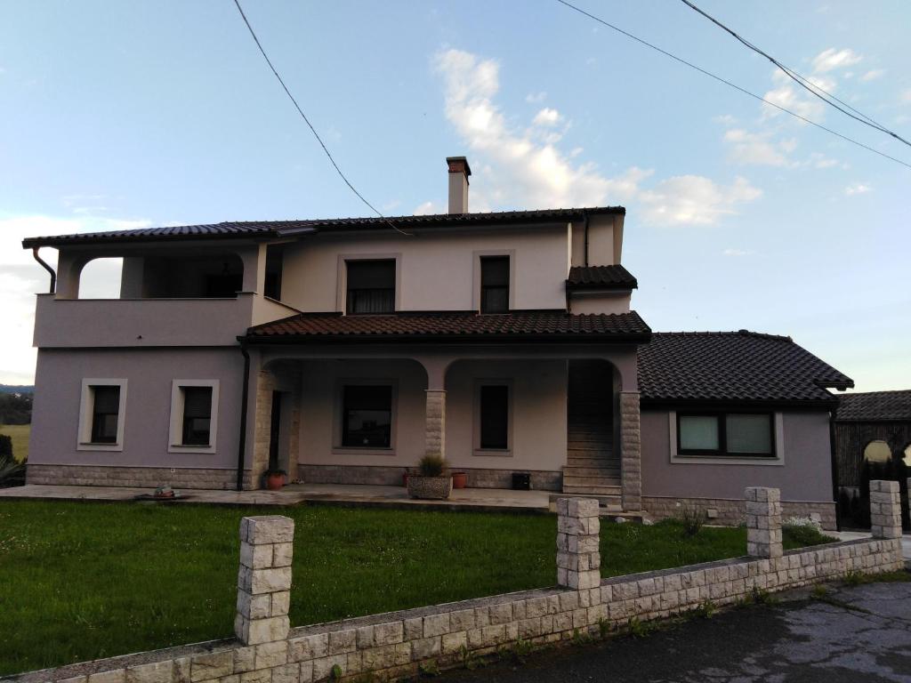 a white house with a fence in front of it at Jasna rooms in Ilirska Bistrica