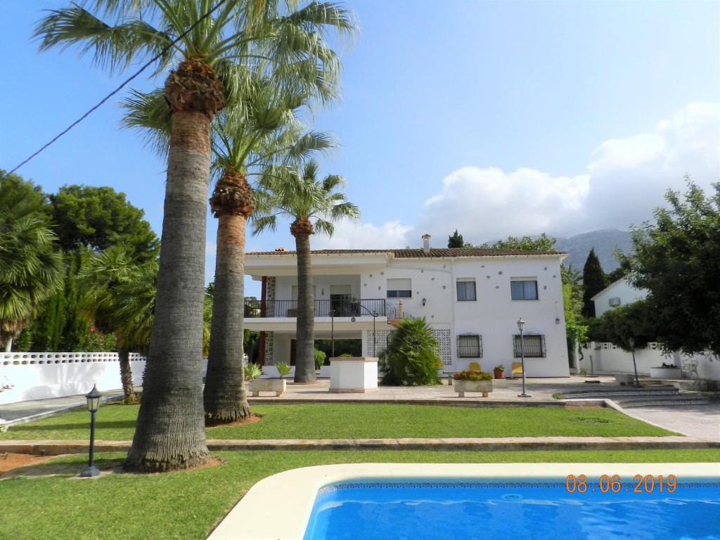 une maison avec des palmiers et une piscine dans l'établissement VILLA EN LES ROTES/LAS ROTAS, PISCINA, à Dénia
