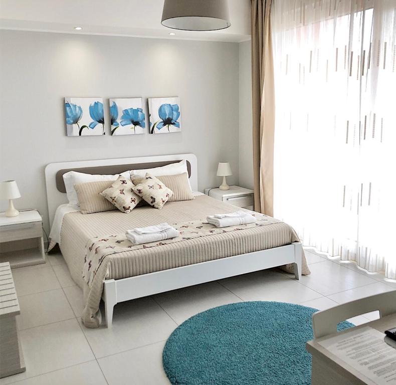 Dormitorio blanco con cama y alfombra azul en Pietra Bianca B&B, en Pachino