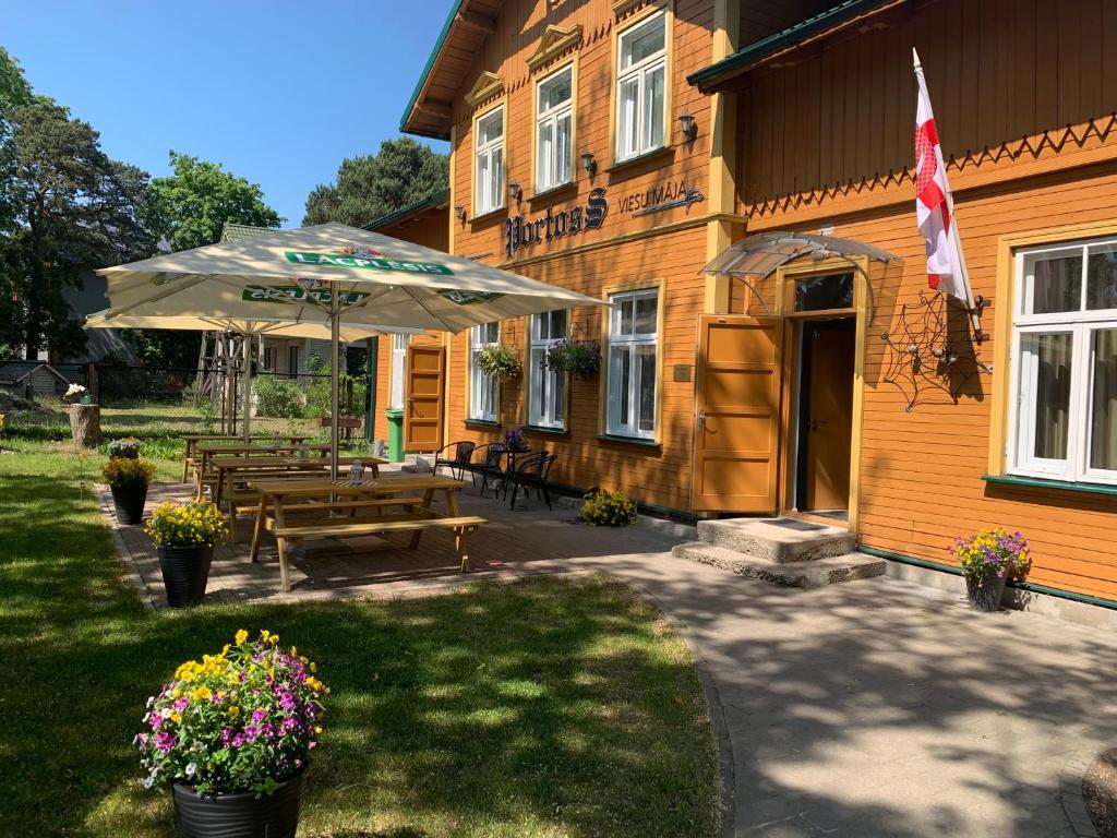 eine Terrasse mit einem Tisch und einem Sonnenschirm außerhalb eines Gebäudes in der Unterkunft Portoss in Ventspils