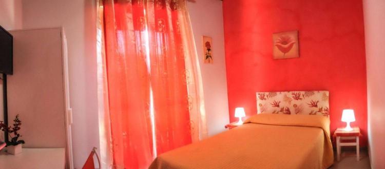 um quarto vermelho com uma cama e uma janela em Mariclà em Viagrande