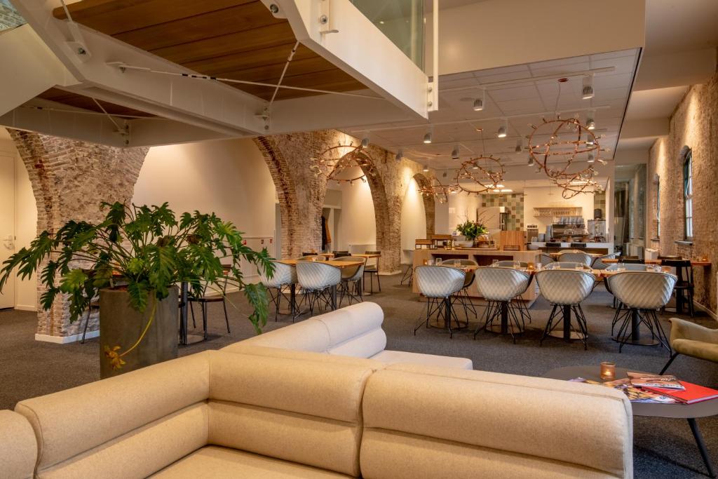 a lobby with a couch and tables and chairs at Onderwijshotel De Rooi Pannen Breda in Breda