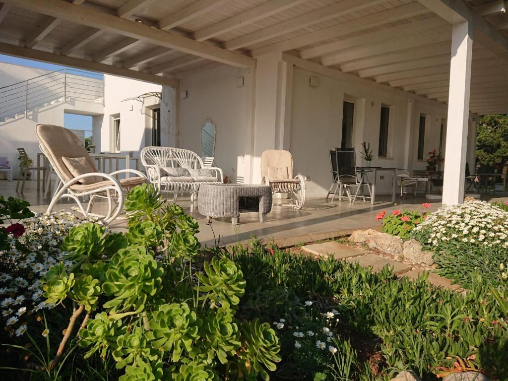 una veranda con sedie e fiori su una casa di LE STELLE DI ARNEO - Casa Vacanze a Torre Lapillo