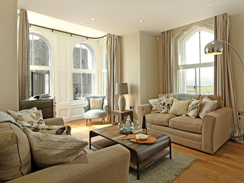 a living room with two couches and a table at Harlech Apartments - Branwen in Harlech