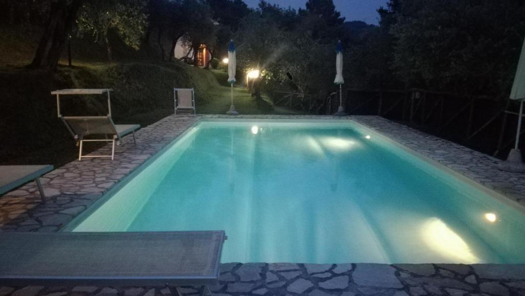 a large swimming pool at night with a chair at Rustico Lo Scarpone in Camaiore