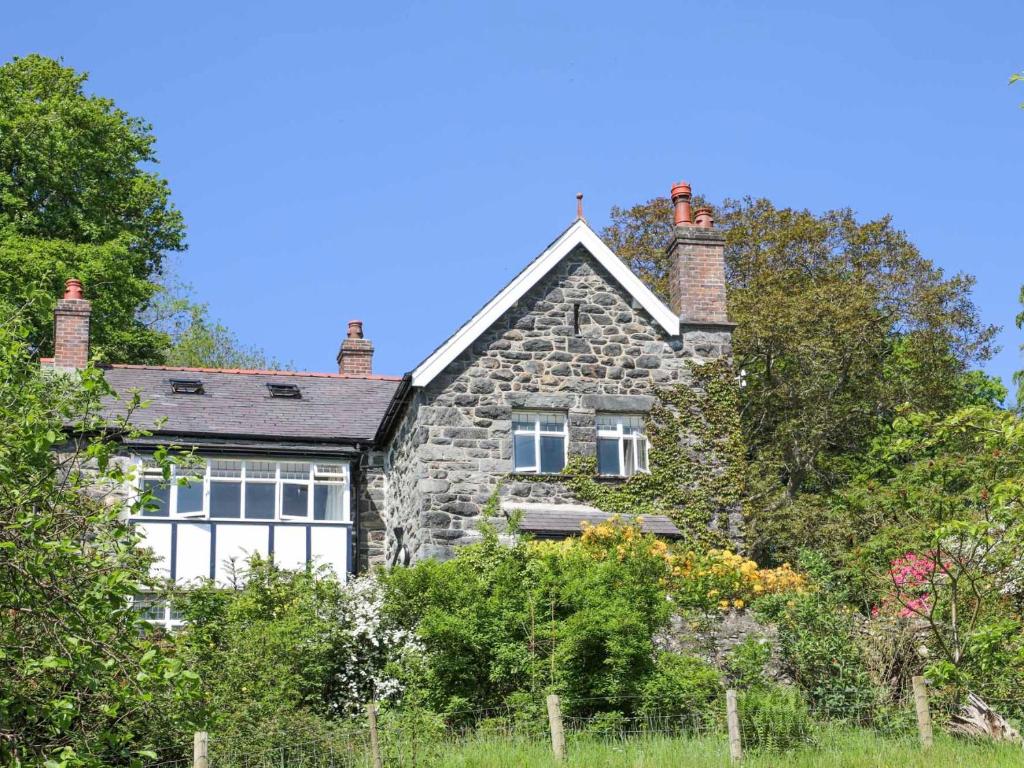 een oud stenen huis met bomen ervoor bij Ty'n y Cae in Llanbedr-y-cennin