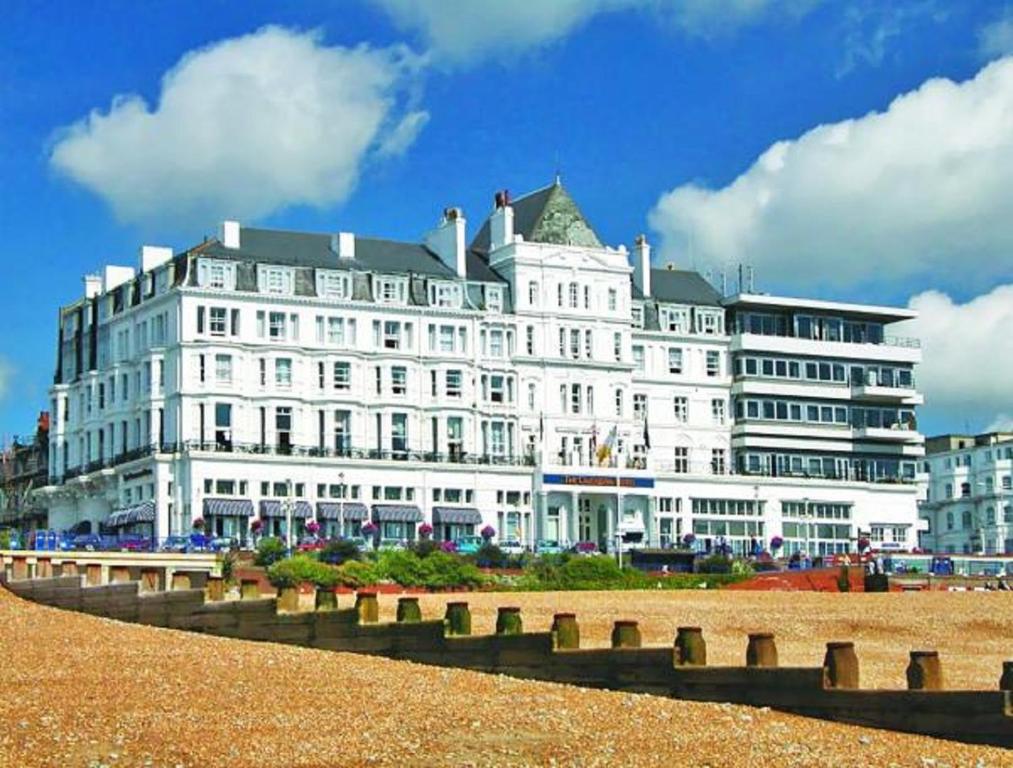 duży biały budynek siedzący na szczycie plaży w obiekcie Cavendish Hotel w mieście Eastbourne