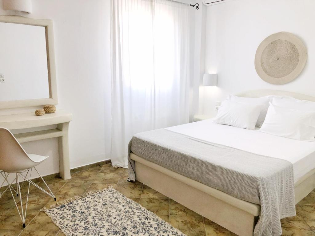 ein weißes Schlafzimmer mit einem Bett und einem Stuhl in der Unterkunft Veletas Apartments in Adamas