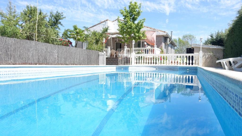 a swimming pool with blue water in front of a house at Villa Flores in Navalcarnero