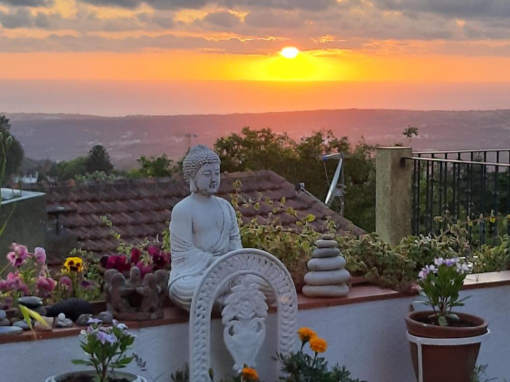 een standbeeld op een muur met een zonsondergang op de achtergrond bij Isa's Home in Sintra