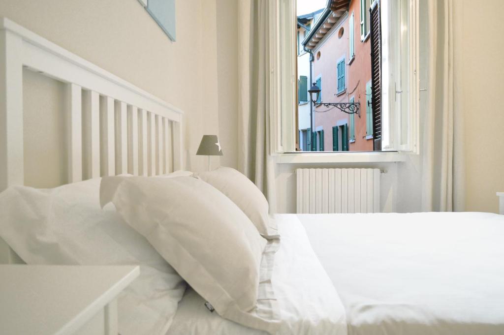 białe łóżko z białymi poduszkami i oknem w obiekcie Stella House w mieście Desenzano del Garda