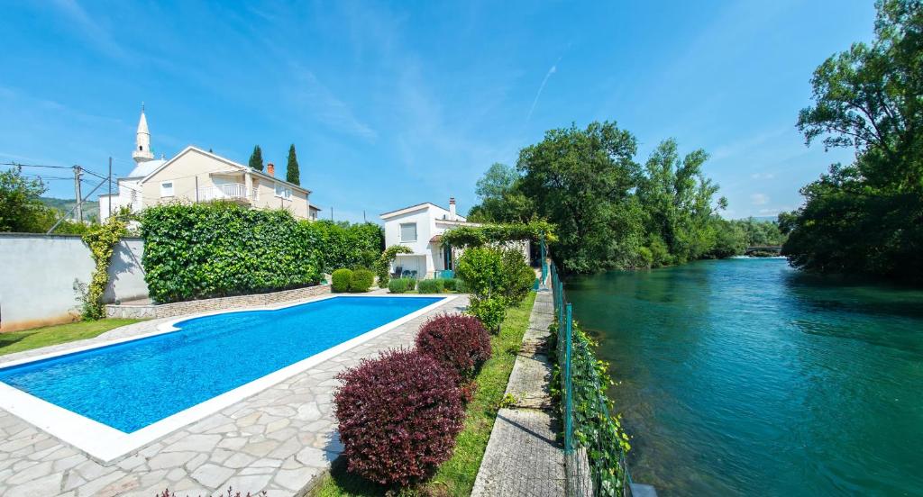 a house with a swimming pool next to a river at Villa Idila in Mostar