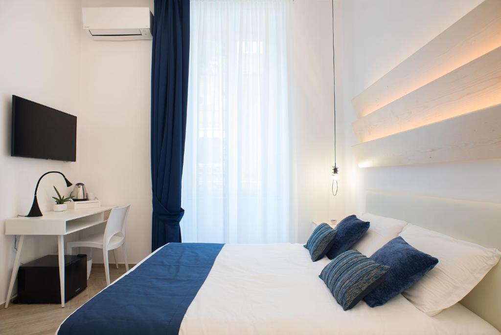 a bedroom with a bed with blue pillows and a desk at Cameo B&B in Naples