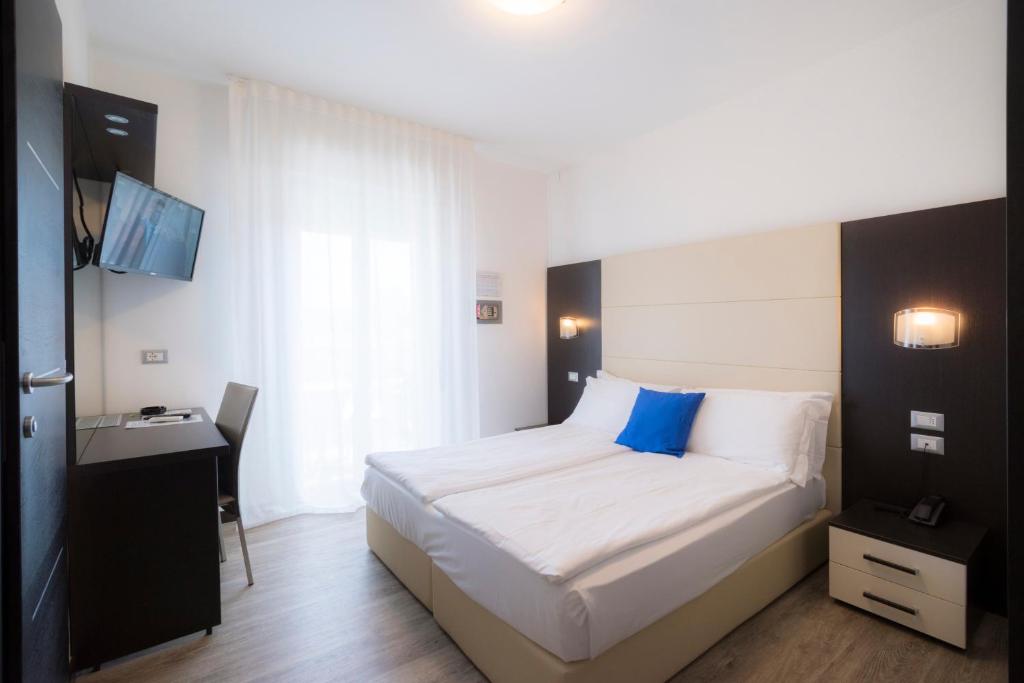 a bedroom with a large bed with a blue pillow at Hotel Bristol in Caorle