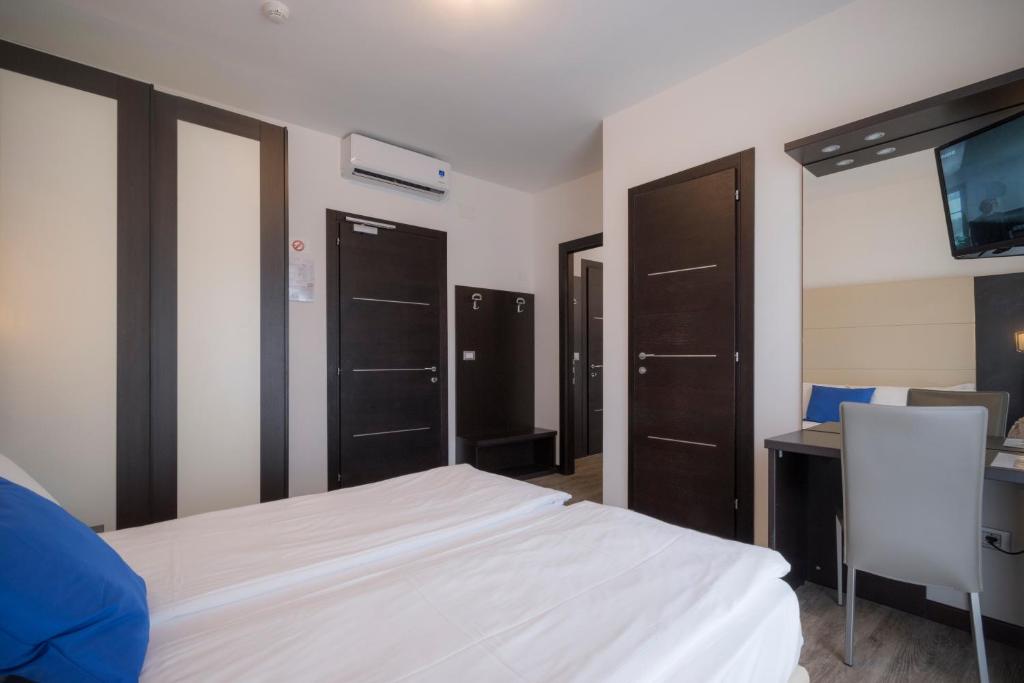 a bedroom with a bed and a desk and a tv at Hotel Bristol in Caorle