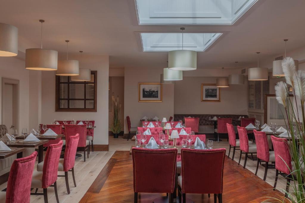 a dining room with red chairs and tables and tablesktop at Glenroyal Hotel in Maynooth