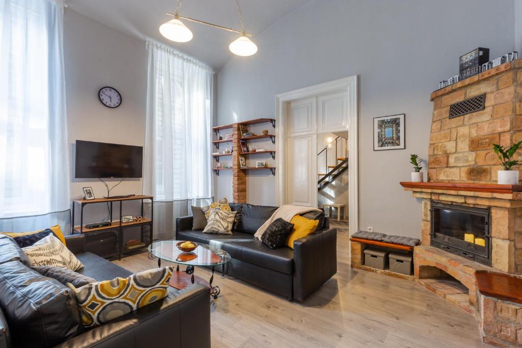 Astoria Heritage Suites في بودابست: غرفة معيشة مع أريكة ومدفأة