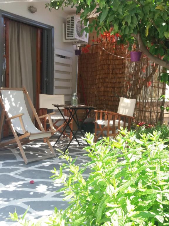 a patio with chairs and a table and a tree at poros apartment in garden in Poros