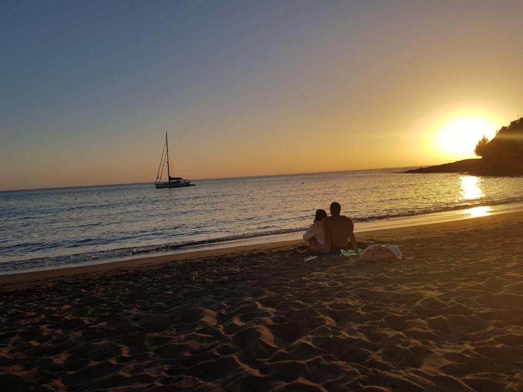 dos personas sentadas en la playa viendo la puesta de sol en Casa Dorotea, en Playa del Cura